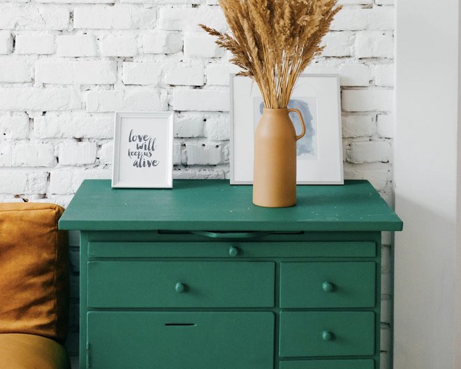 green chest of drawers with a flower vase on top